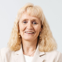 Vaaleahiuksinen nainen tummassa mekossa.