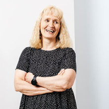 Vaaleahiuksinen nainen tummassa mekossa.