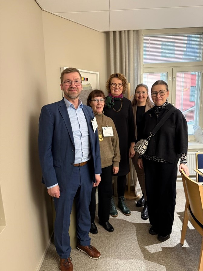 Neljä naista ja yksi mies poseeraavat kameralle.