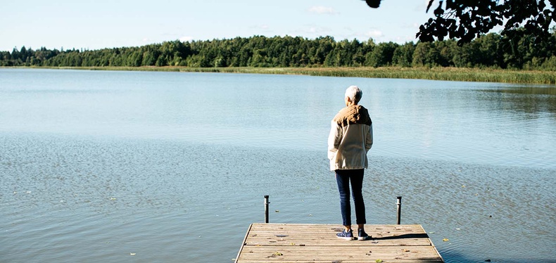 Nainen katselee laiturilla järvelle.
